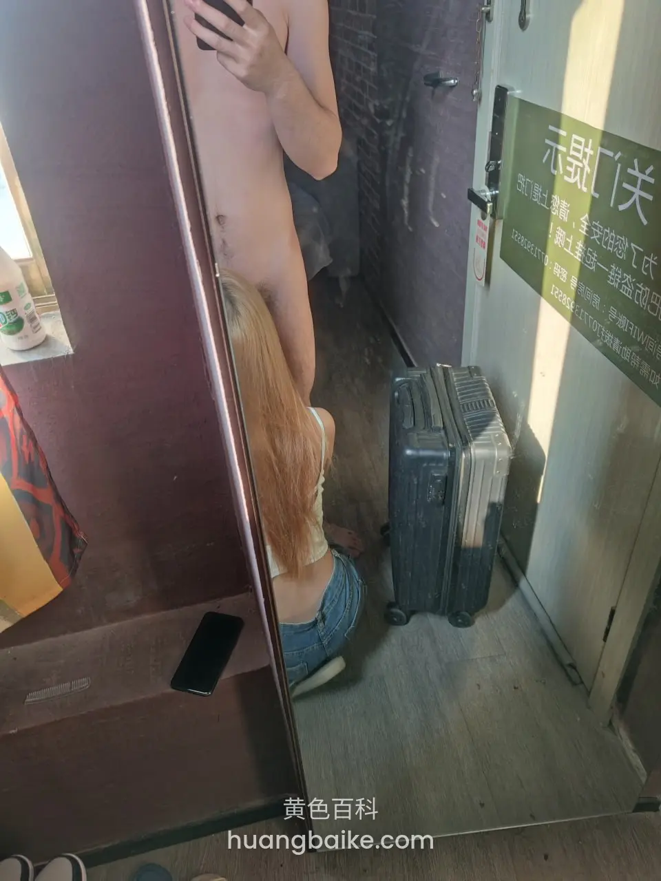 酒店门口镜子前，地上放着行李箱