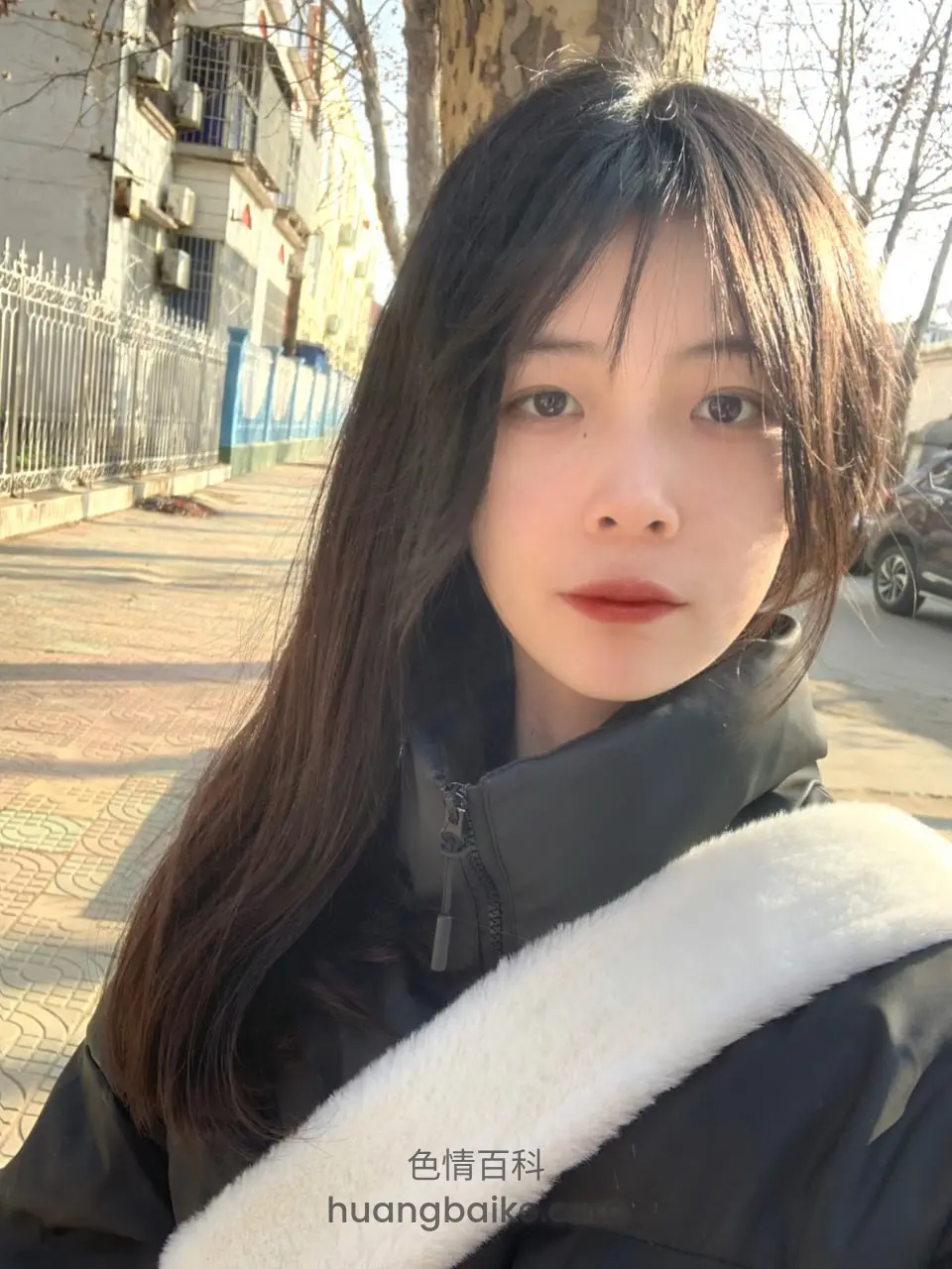 街边树下拍自拍，身后是围栏和楼