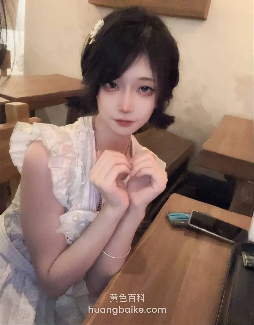 咖啡馆桌前双手比心，手机放旁边