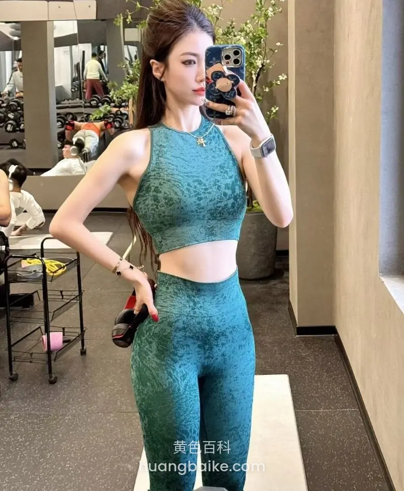 健身房镜子前举手机自拍，左手拿着哑铃