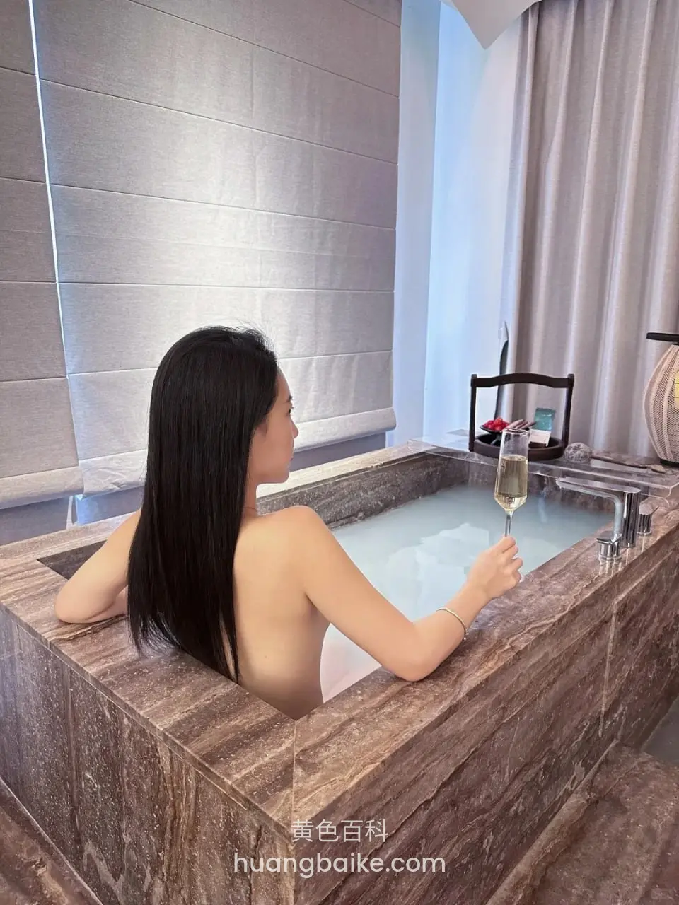 浴缸里侧身举着香槟，镜头对着水龙头