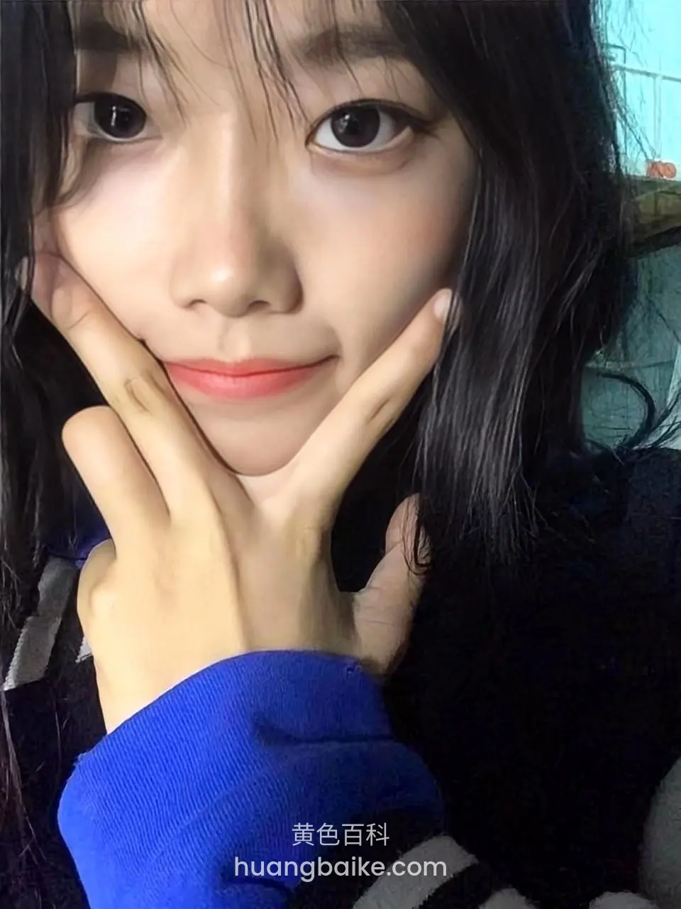 黑发女生双手捧脸微笑