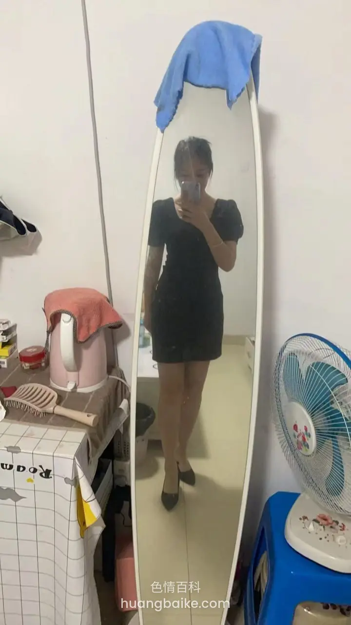 房间镜子里黑裙女子拿着手机自拍