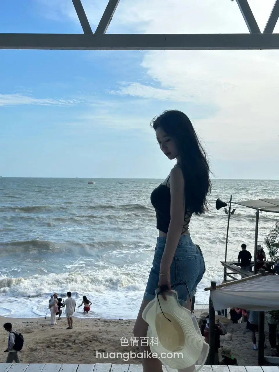 海边木亭下，拿着白色帽子看海