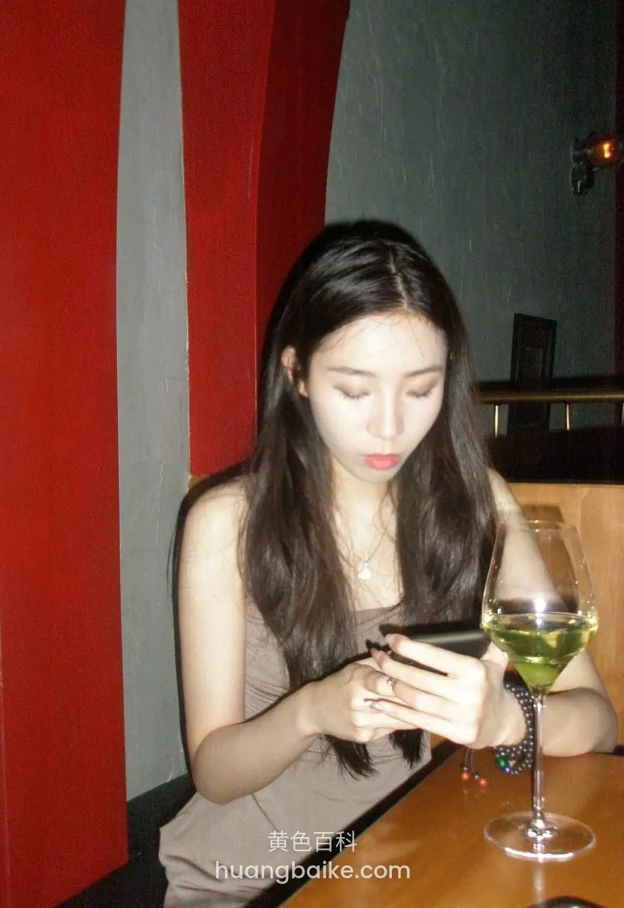 餐桌边玩手机，旁边一杯绿酒