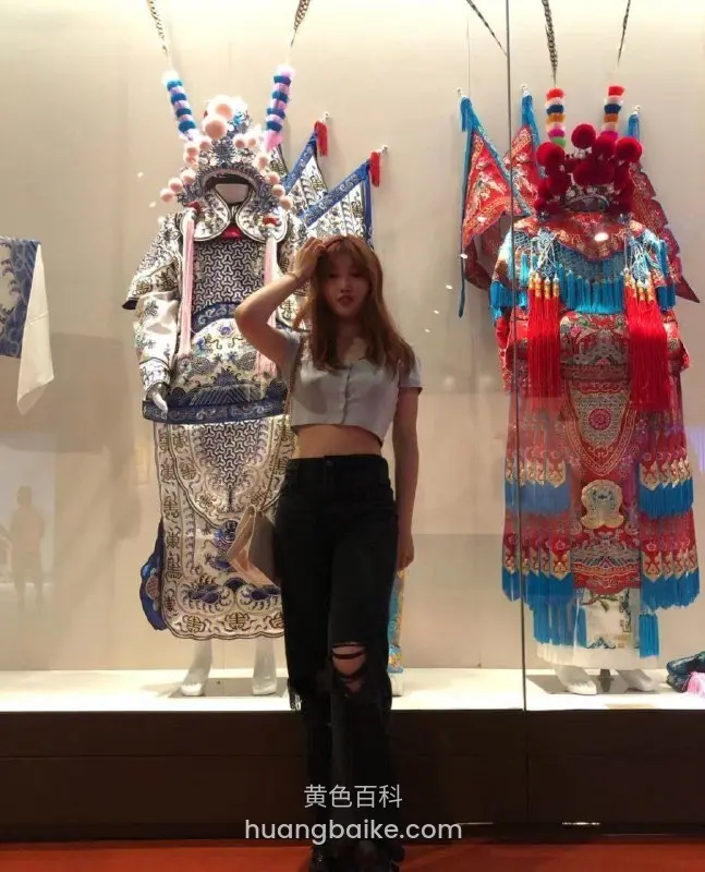 女生比剪刀手站在京剧戏服展柜前