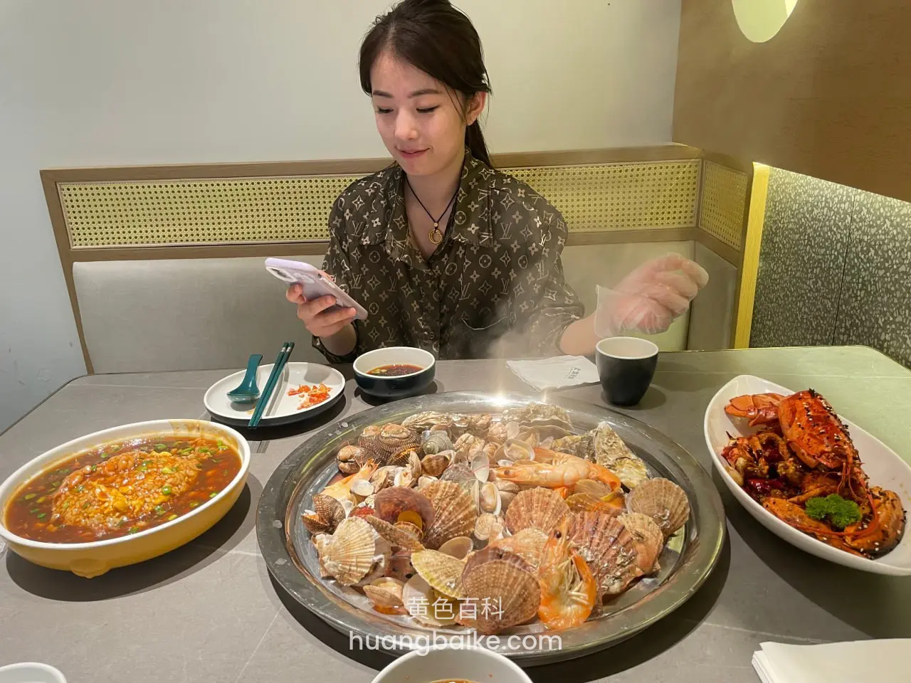 餐厅桌前看手机，桌上摆满海鲜