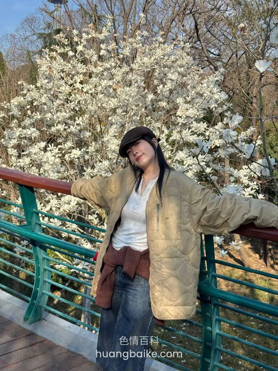 靠着公园绿栏杆张开双臂，背后玉兰花树开满白花