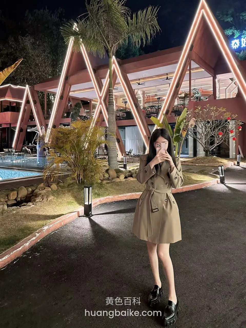 夜间度假村前站立，手机挡住半张脸