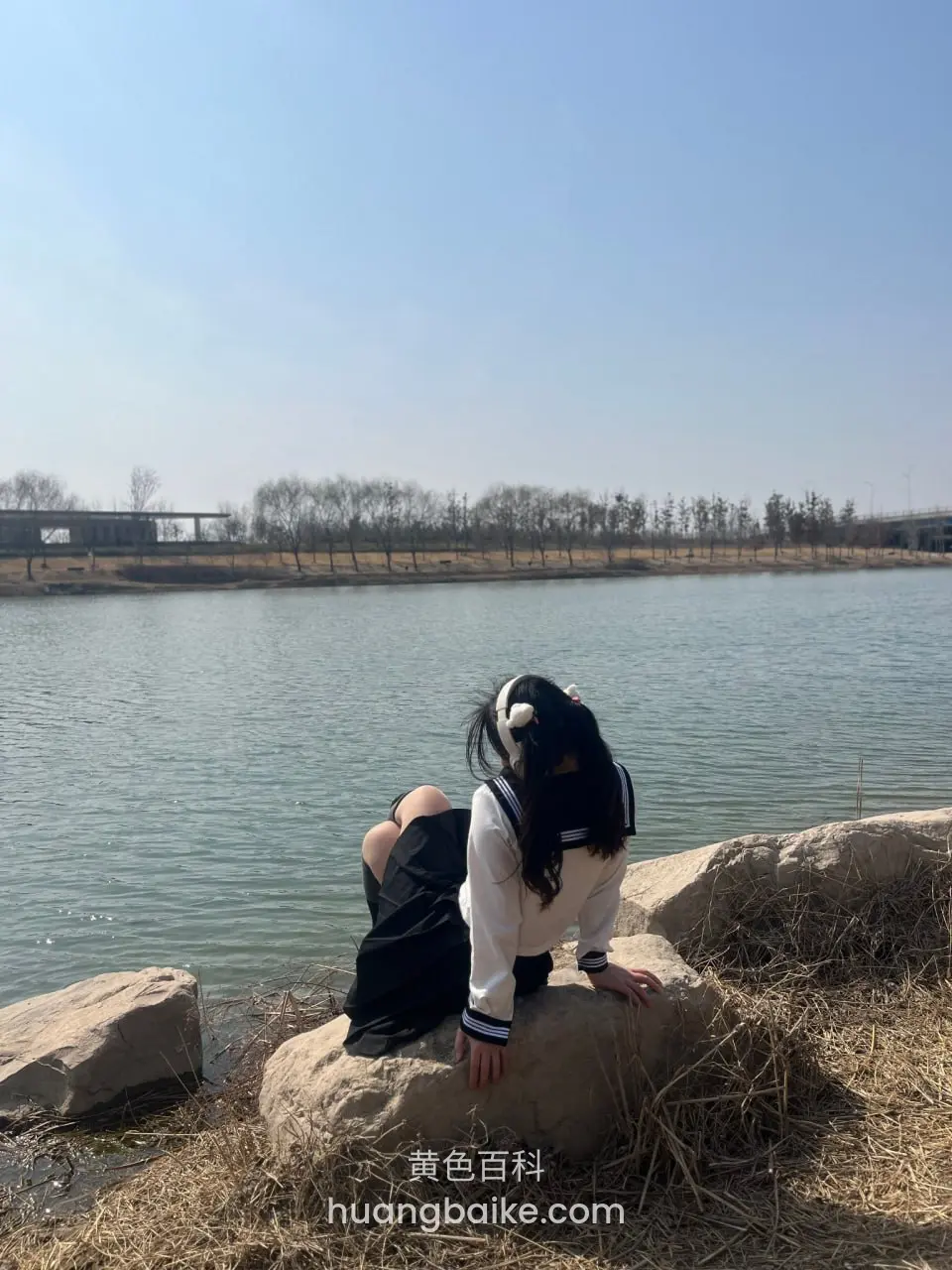 湖边大石头上坐着，身后大片水面