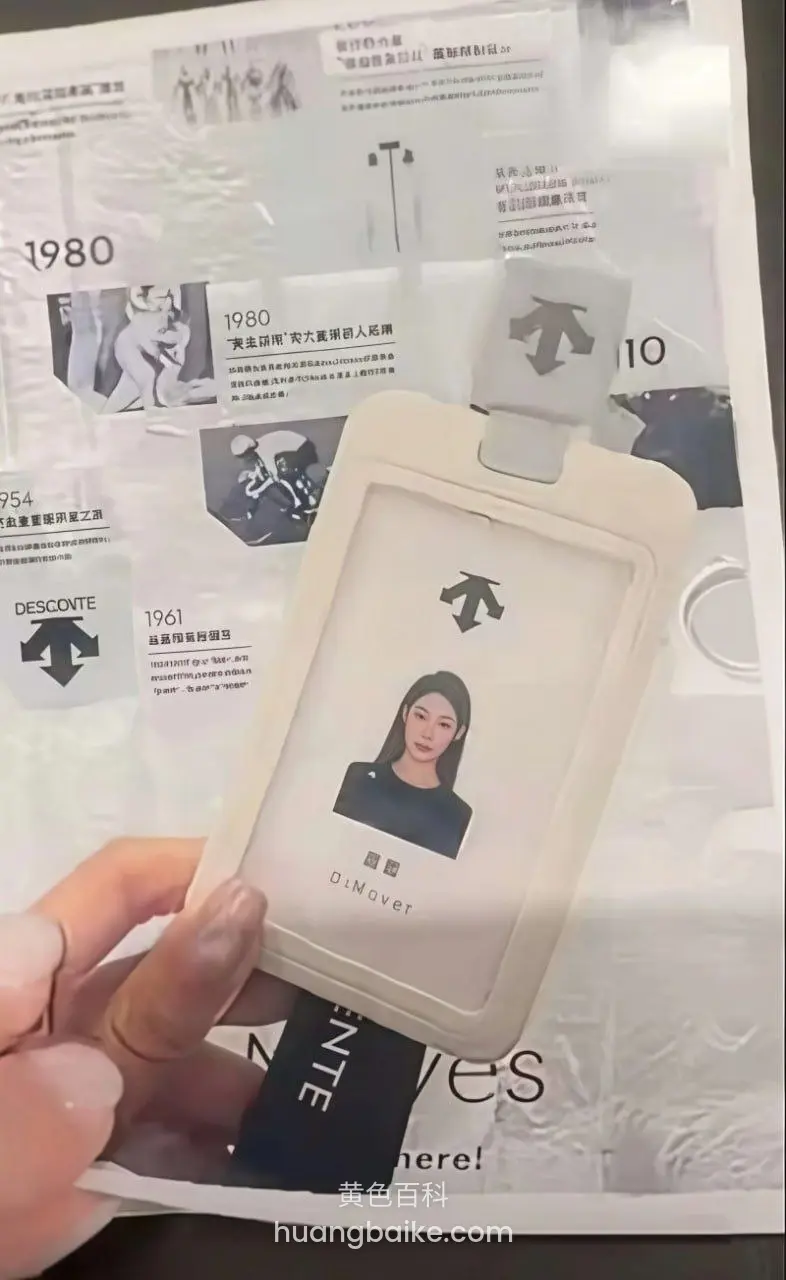 手指捏着员工卡，背景是品牌历史海报