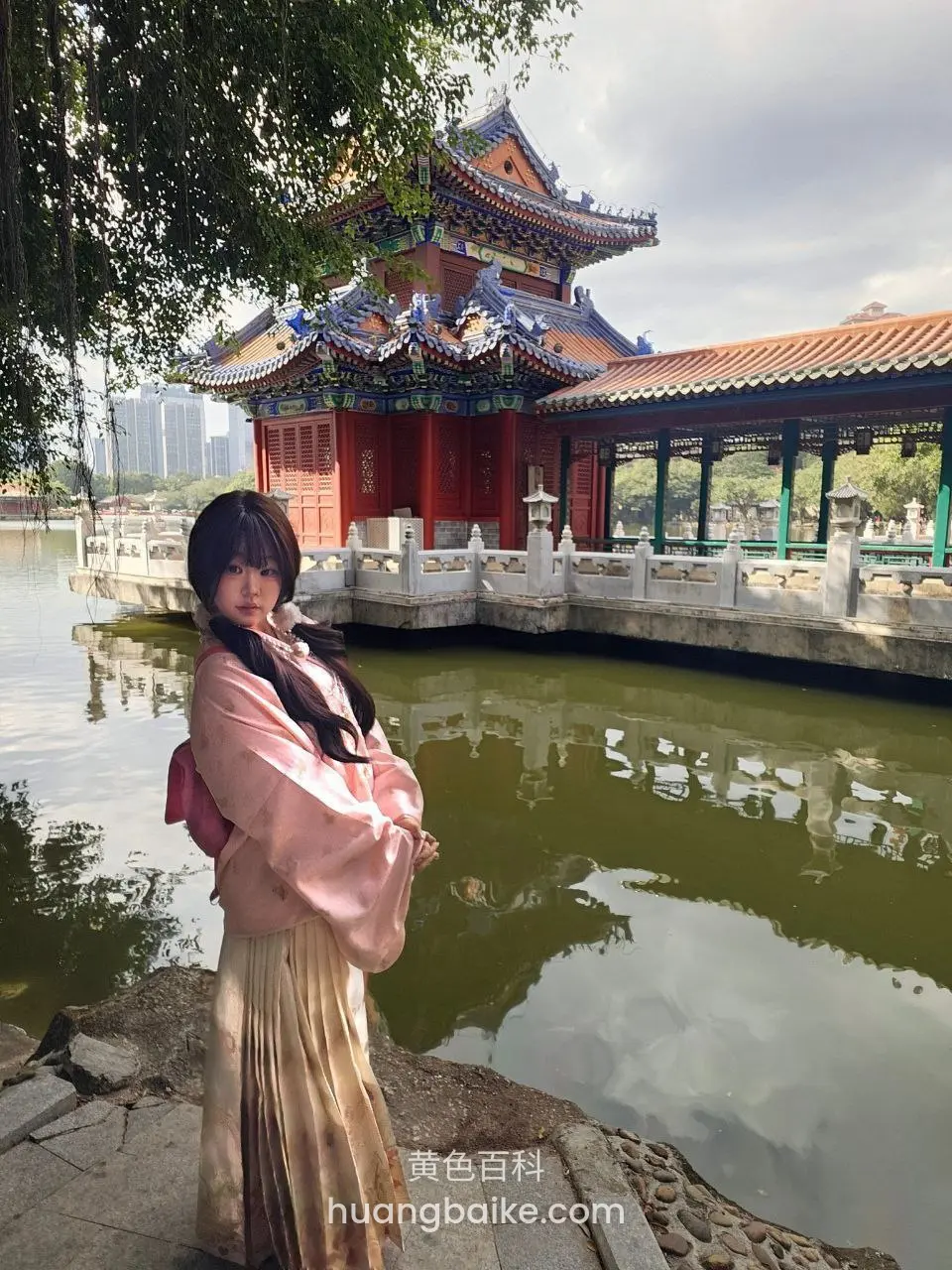 湖边古典建筑前站立，双手抱胸看镜头