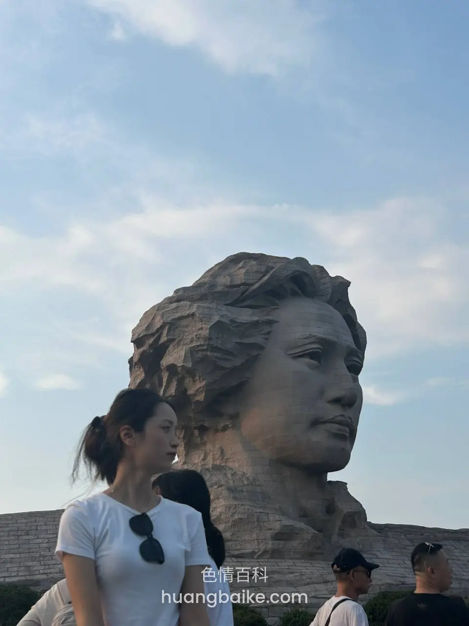 镜头仰拍毛主席像，前面女生回头看