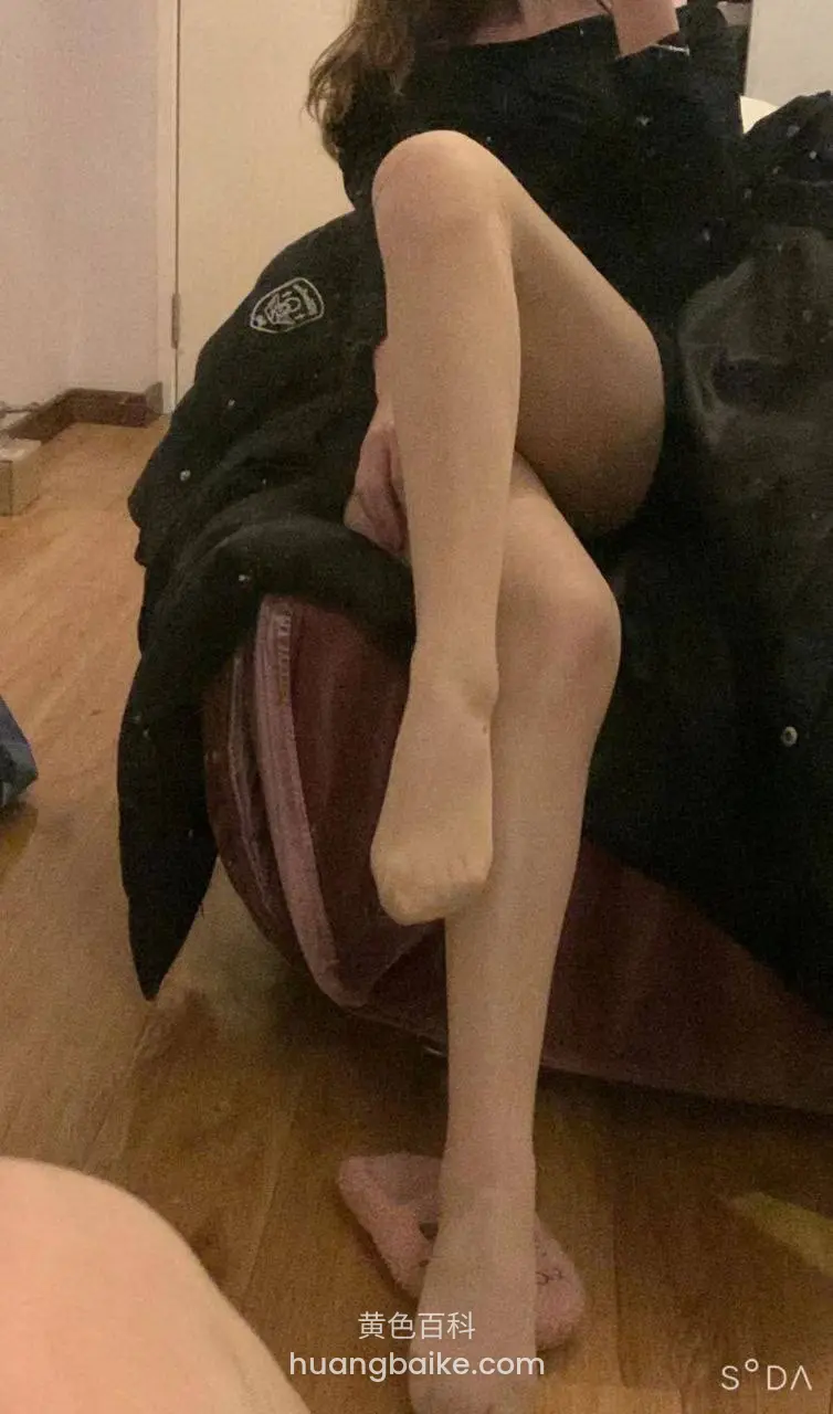 黑衣人坐行李箱，镜头对着光腿和脚