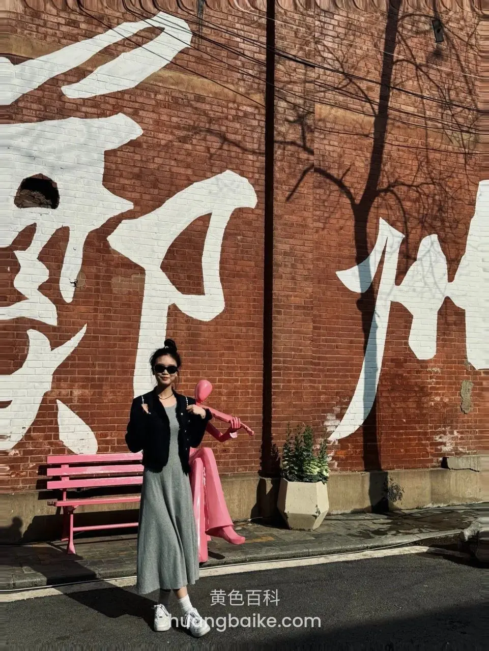 镜头对着红砖墙白字,墙前粉色长椅