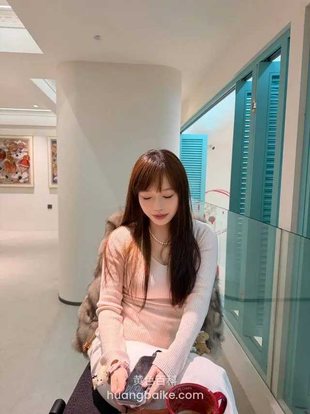 艺术馆里拿着手机低头坐，旁边红杯子