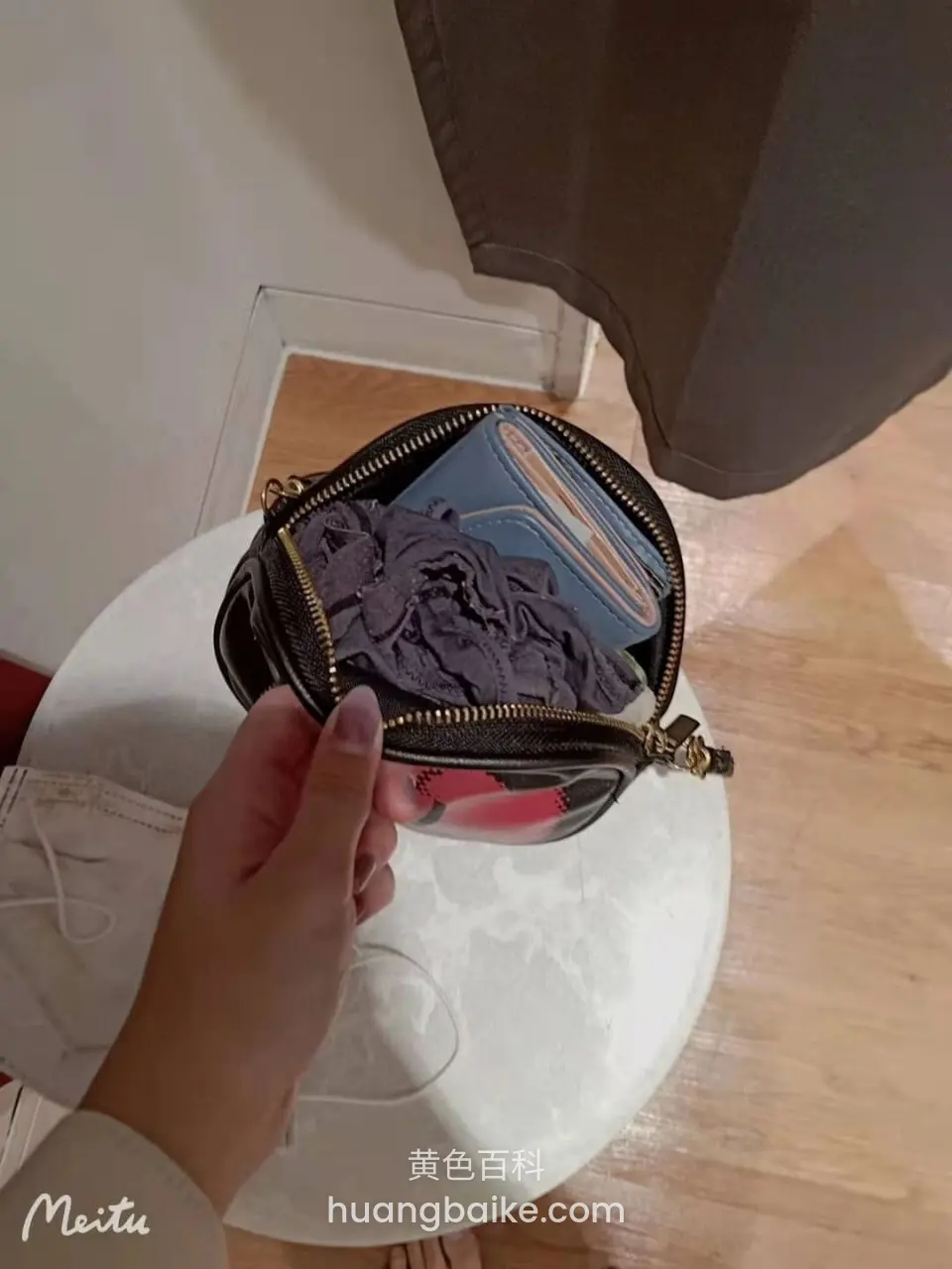 圆桌上手提打开的包，里面塞着紫色衣服和卡包