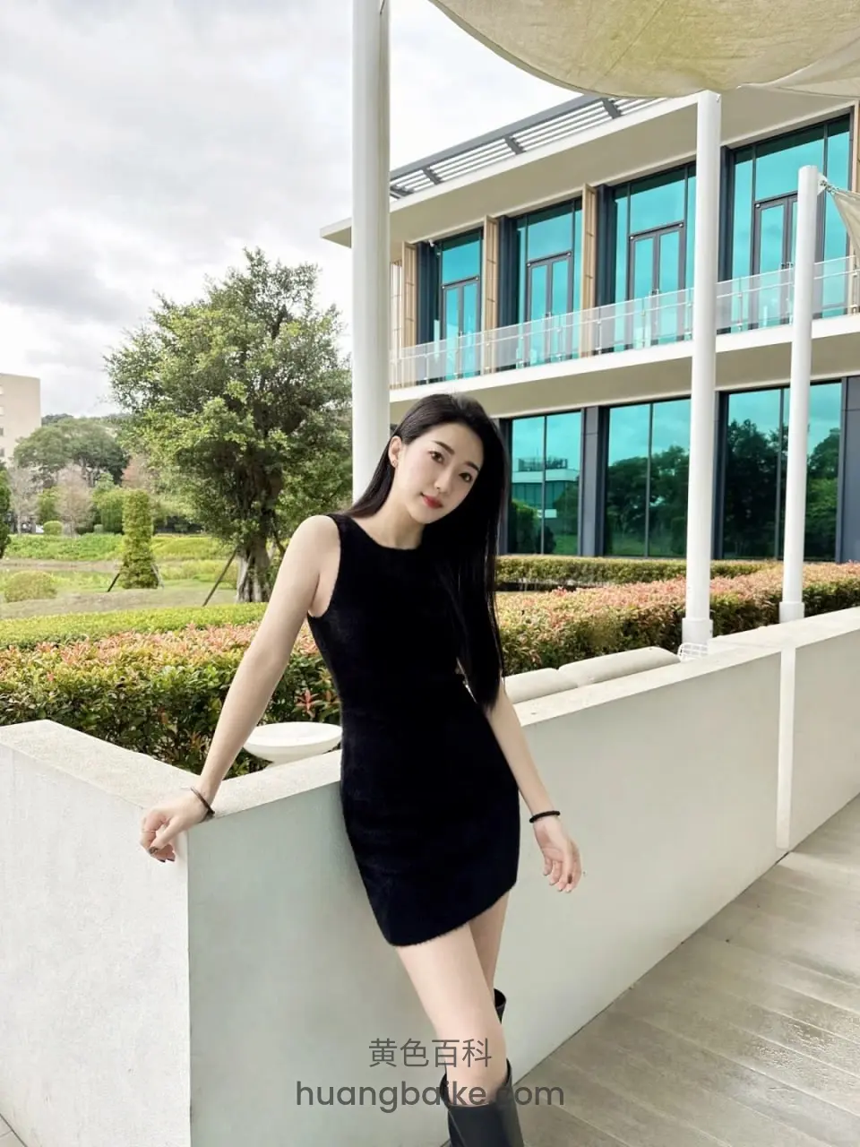 户外白色栏杆边站立，背景是现代建筑花园