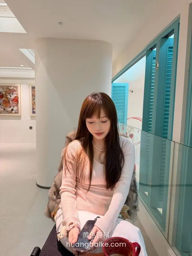 拿着手机低头坐在窗边