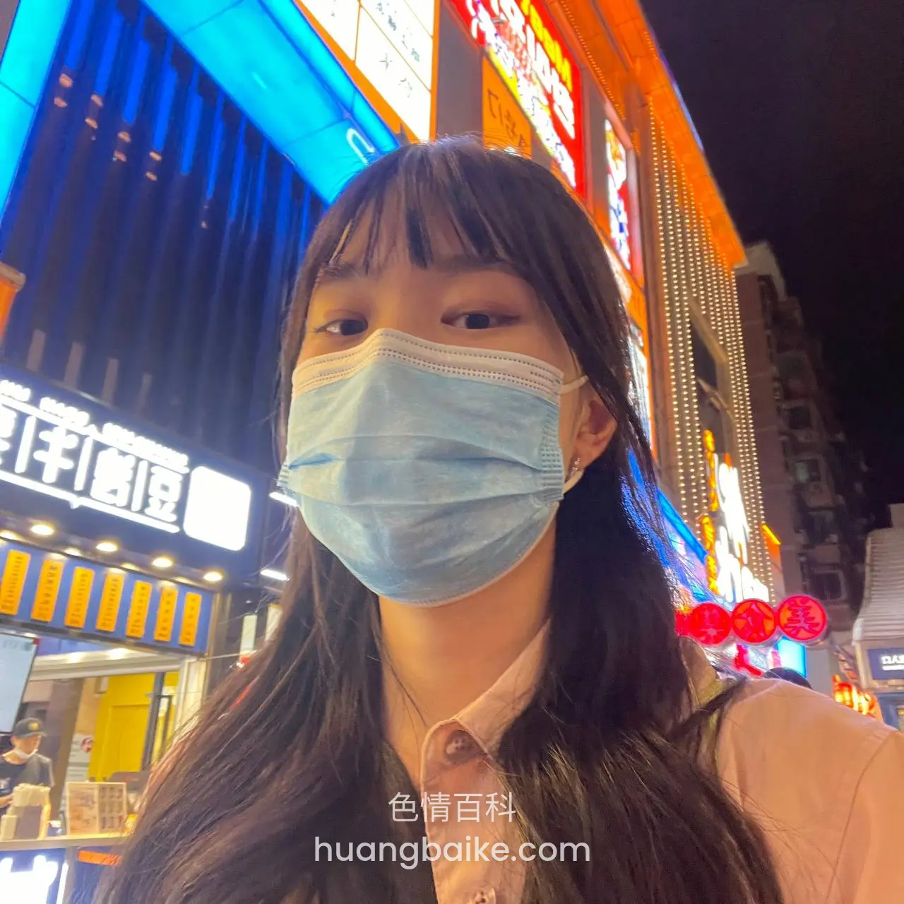 夜晚街头戴口罩自拍，身后是亮招牌