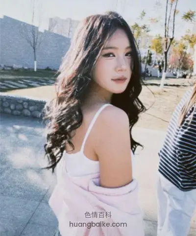 回头看镜头，身后是建筑和树木