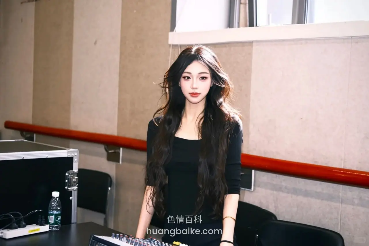 设备桌前站立，桌上放着调音台和水瓶