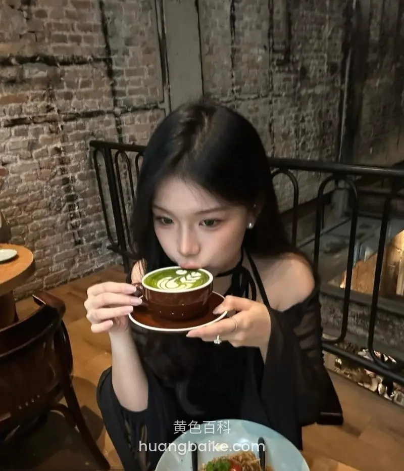 镜头对着捧着拿铁咖啡杯，杯上拉花图案