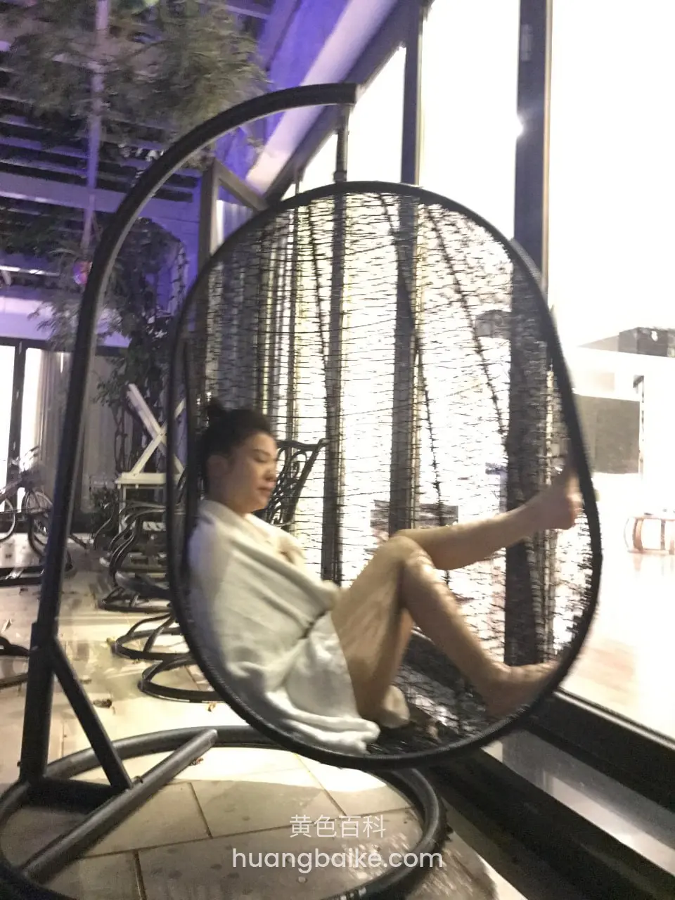 吊椅上躺着玩手机，脚搭在网边