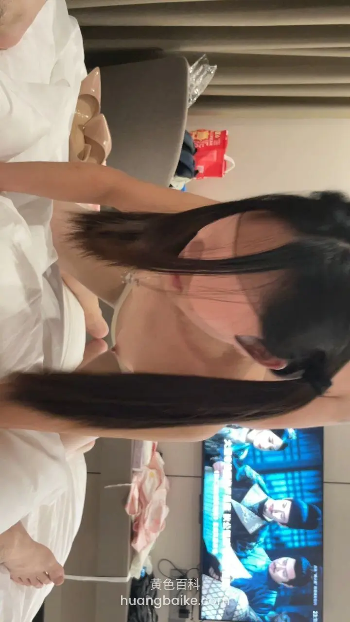 床上低头撩头发，身后电视播放节目
