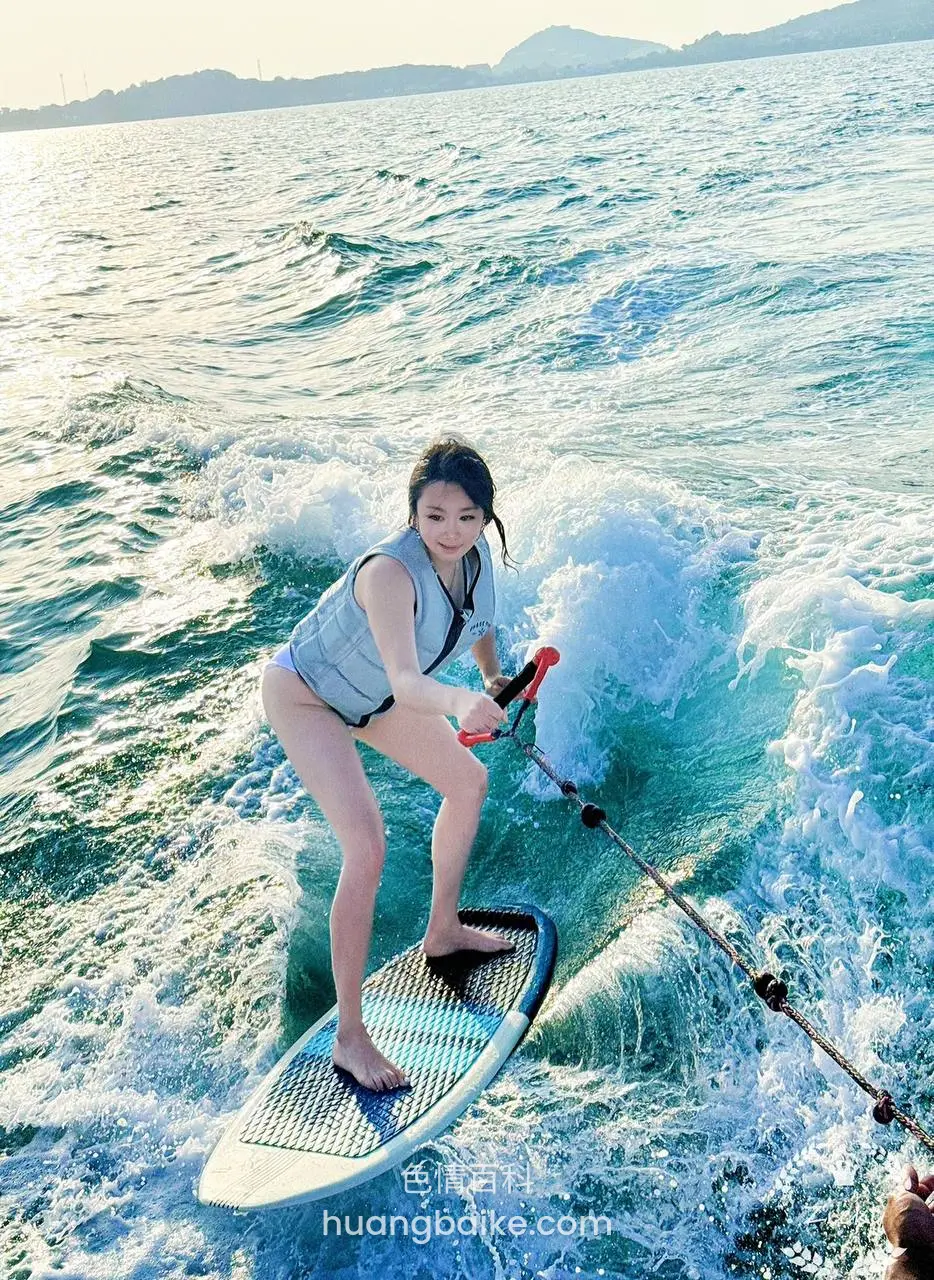 海里抓住绳子站在冲浪板上，身后是浪花