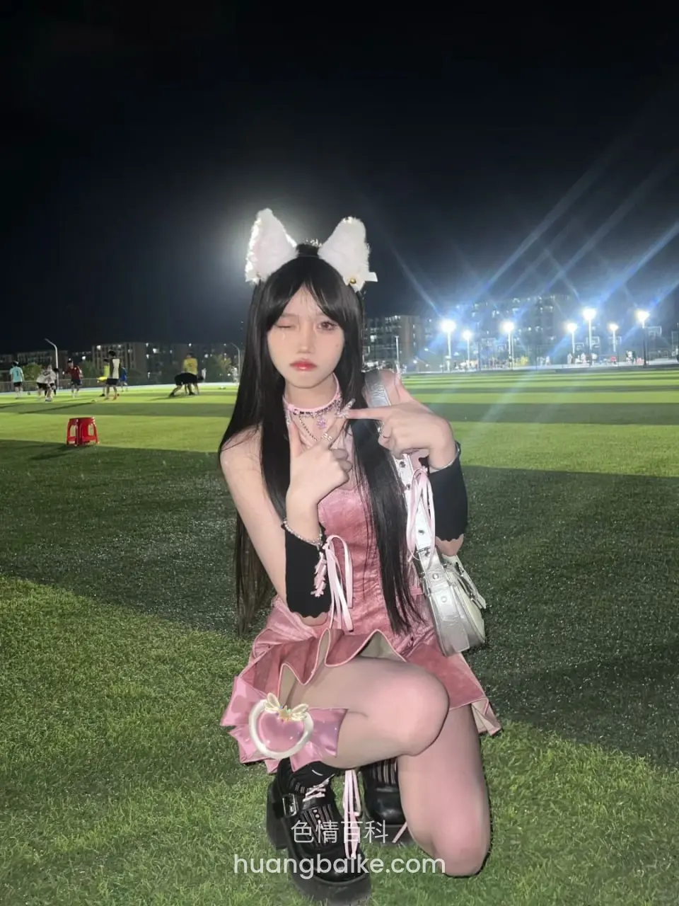 夜间球场跪姿，手机举在脸旁