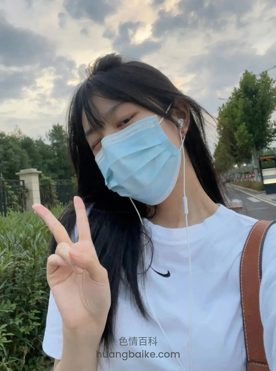 户外路边举手比耶，背景有绿树
