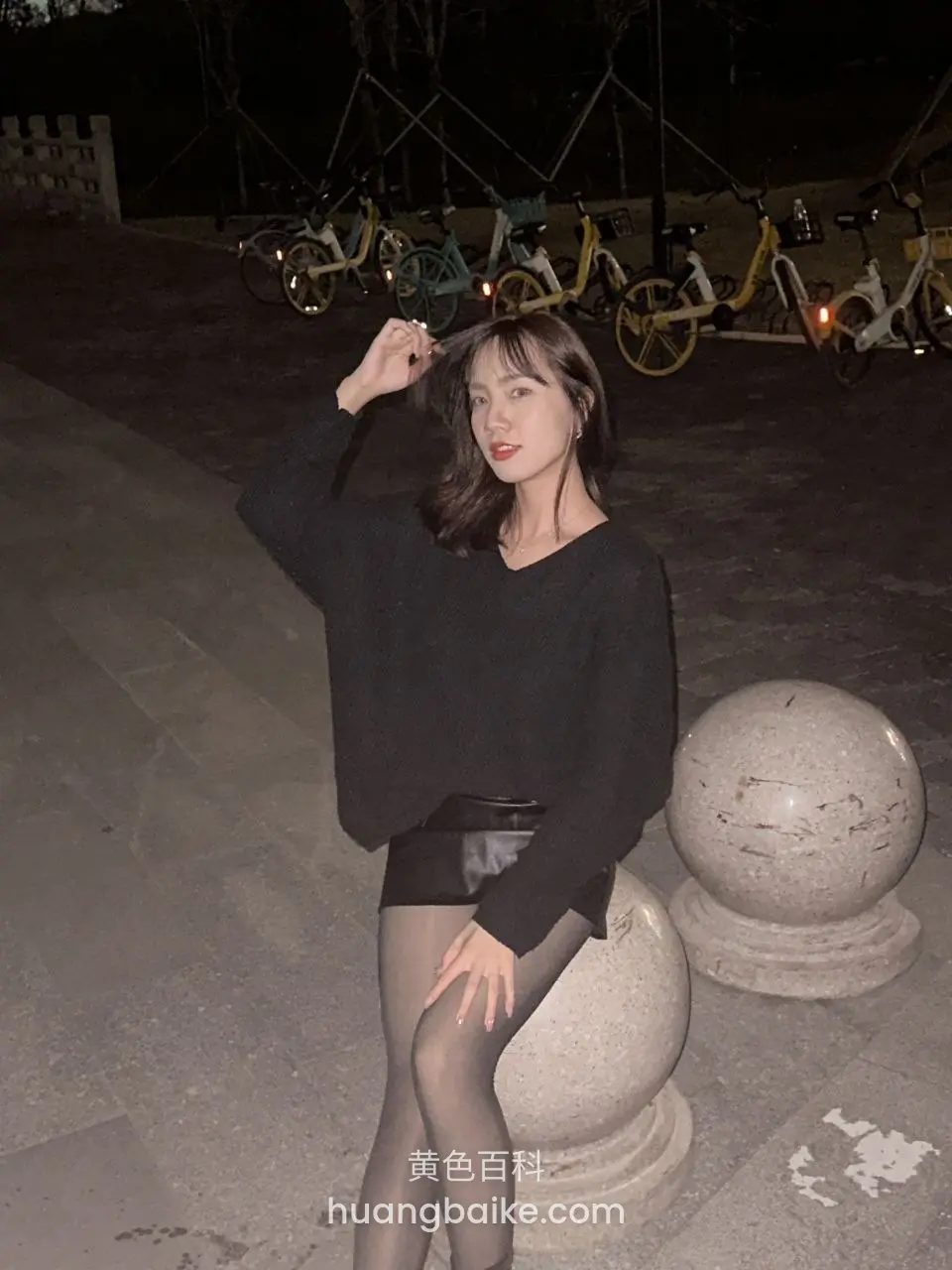 夜里石球上坐着，面前停一排共享单车