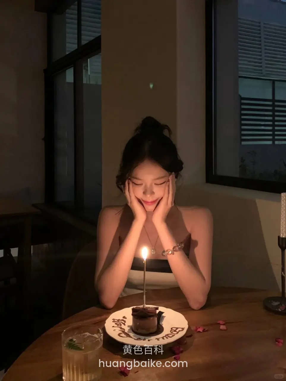 桌上小蛋糕前双手托脸看烛光