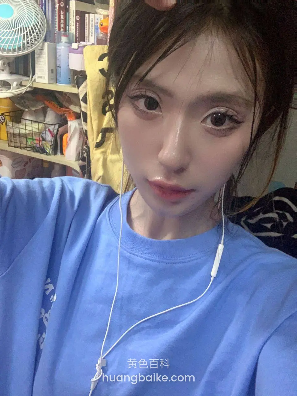 蓝T恤戴白耳机，书架前举手机自拍