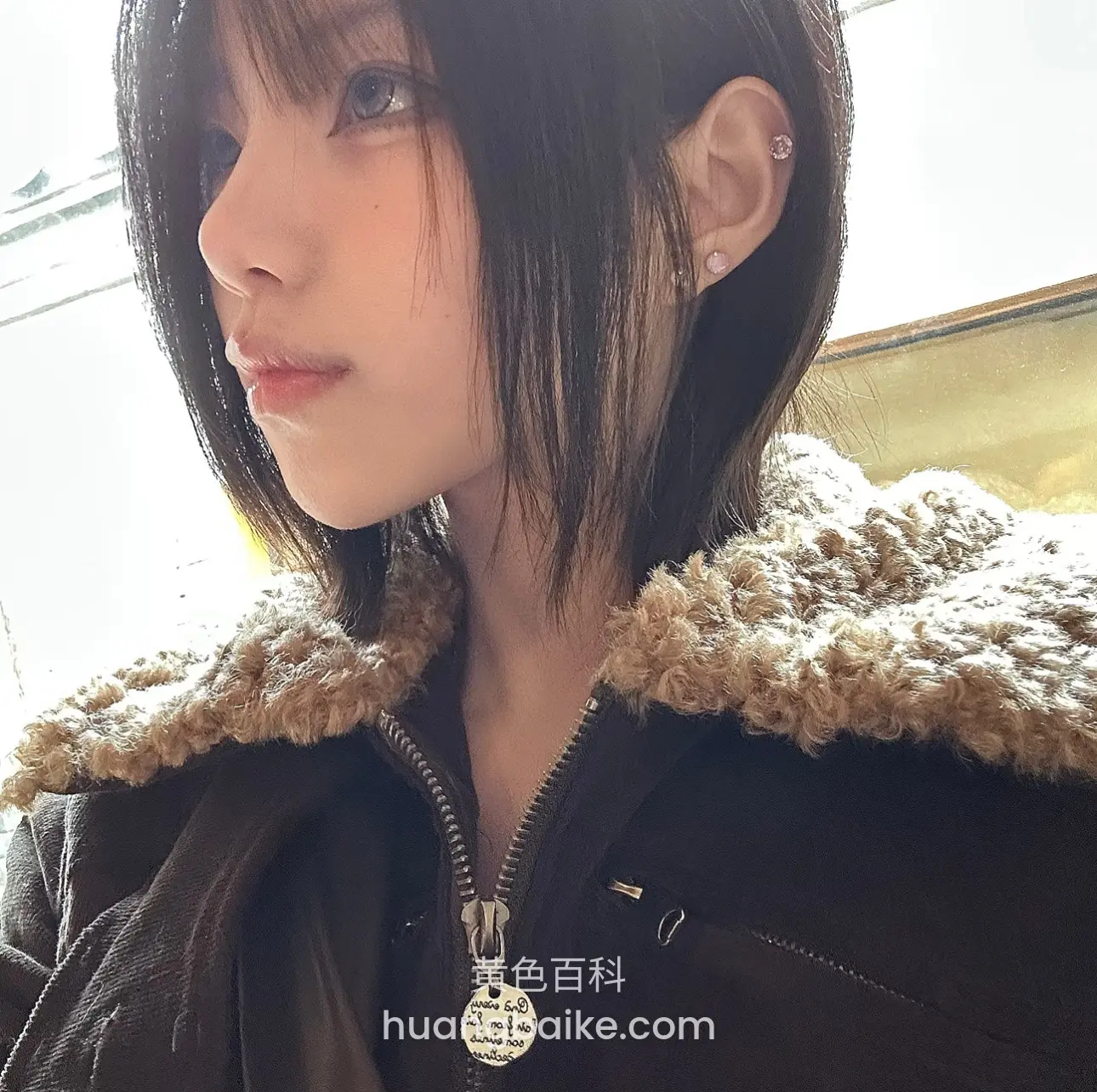 窗边侧脸特写，黑色外套毛领拉链挂着圆牌