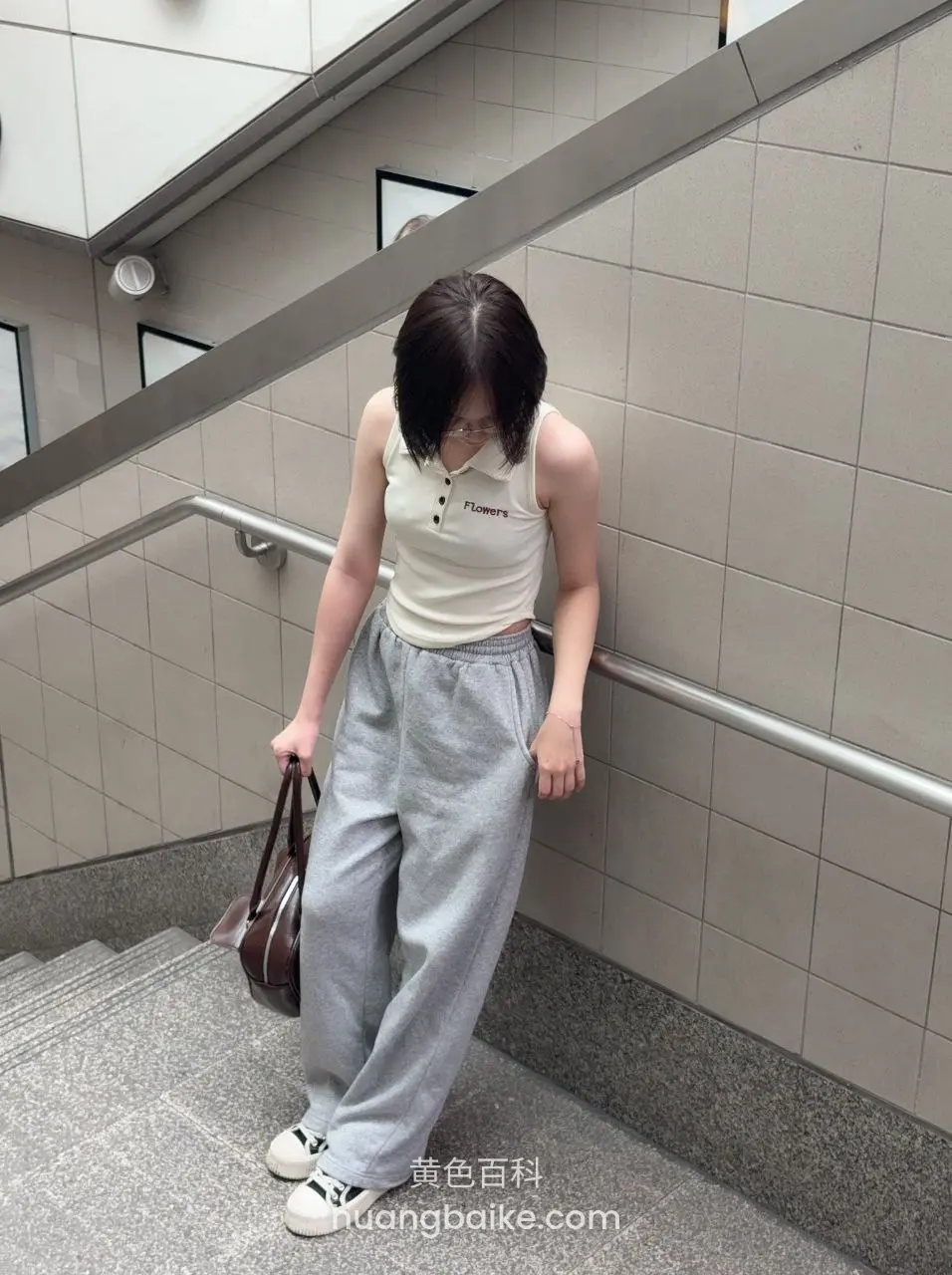 楼梯间站着低头，左手拎包