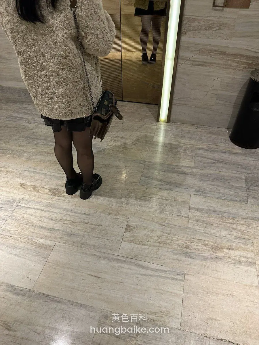 酒店大理石地面，毛衣配黑短裤站在全身镜前，镜子映出下半身