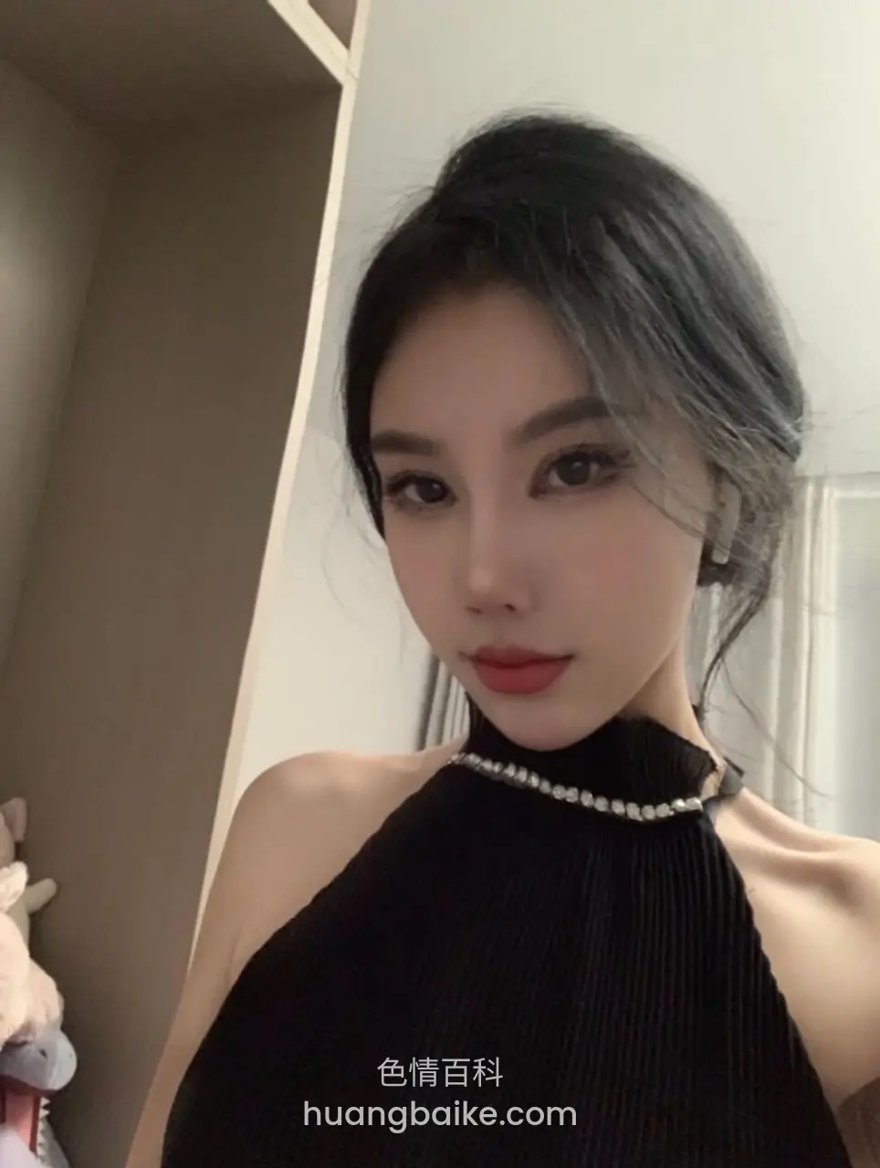 卧室里对着镜子，戴珍珠项链的黑上衣