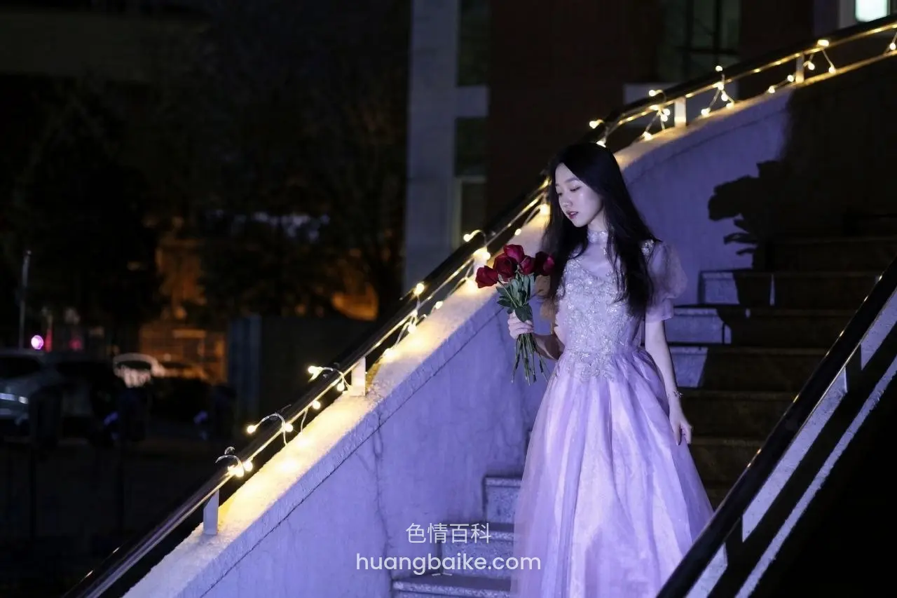 夜晚楼梯扶手边走下，手里拿着红玫瑰花束