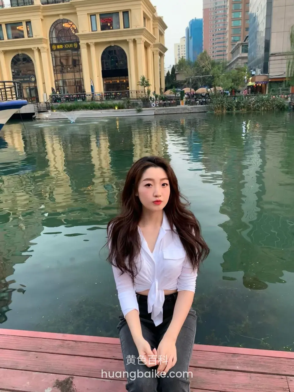 城市河边木板上坐下，身后建筑倒影水里