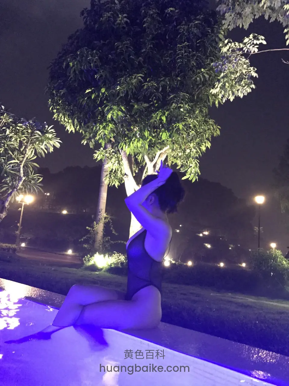 泳池边树下坐着，手举过头顶