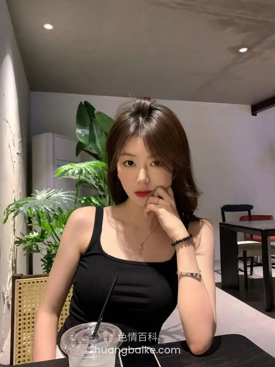 咖啡厅里托着下巴看镜头，桌上放着奶茶