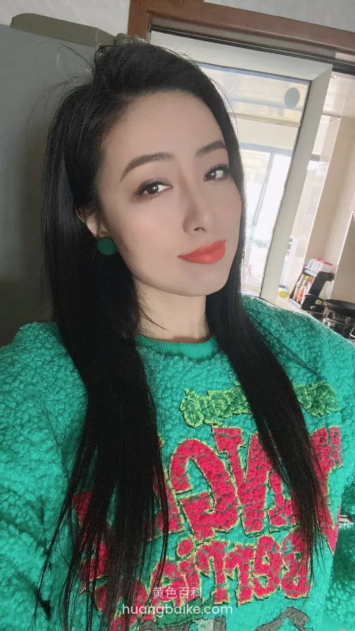 厨房窗边举手机，穿绿色毛衣写着字