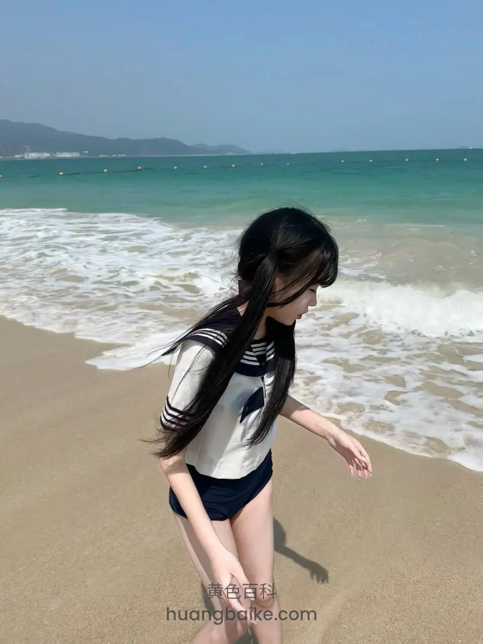 沙滩上低头走，身后是海浪