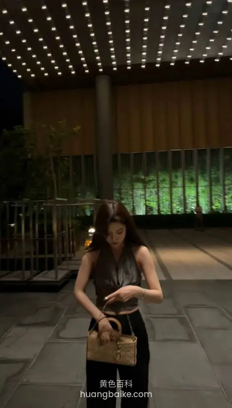 户外夜景广场，低头看手机，包拿在左手