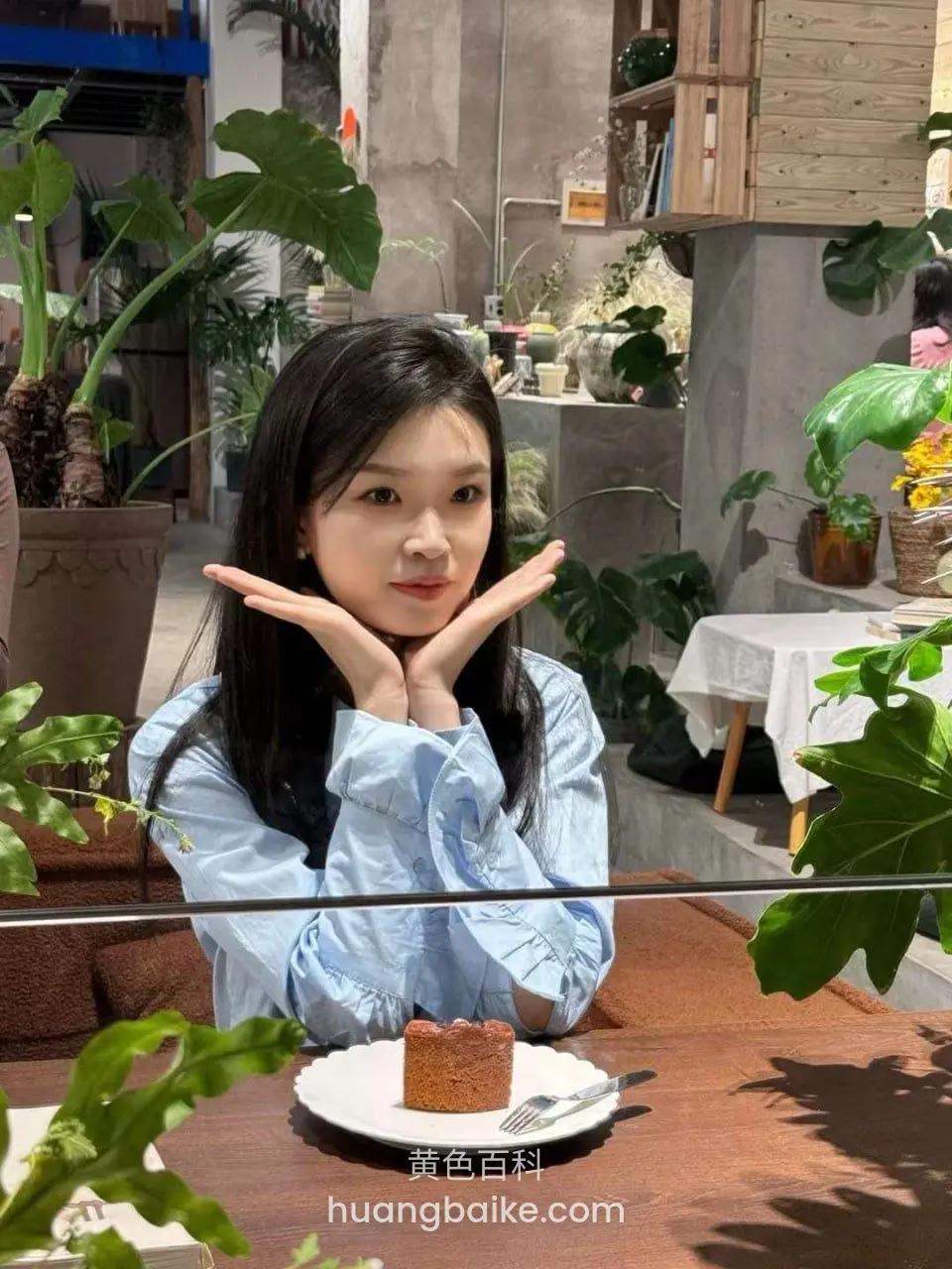咖啡厅里双手托脸,桌上放着蛋糕