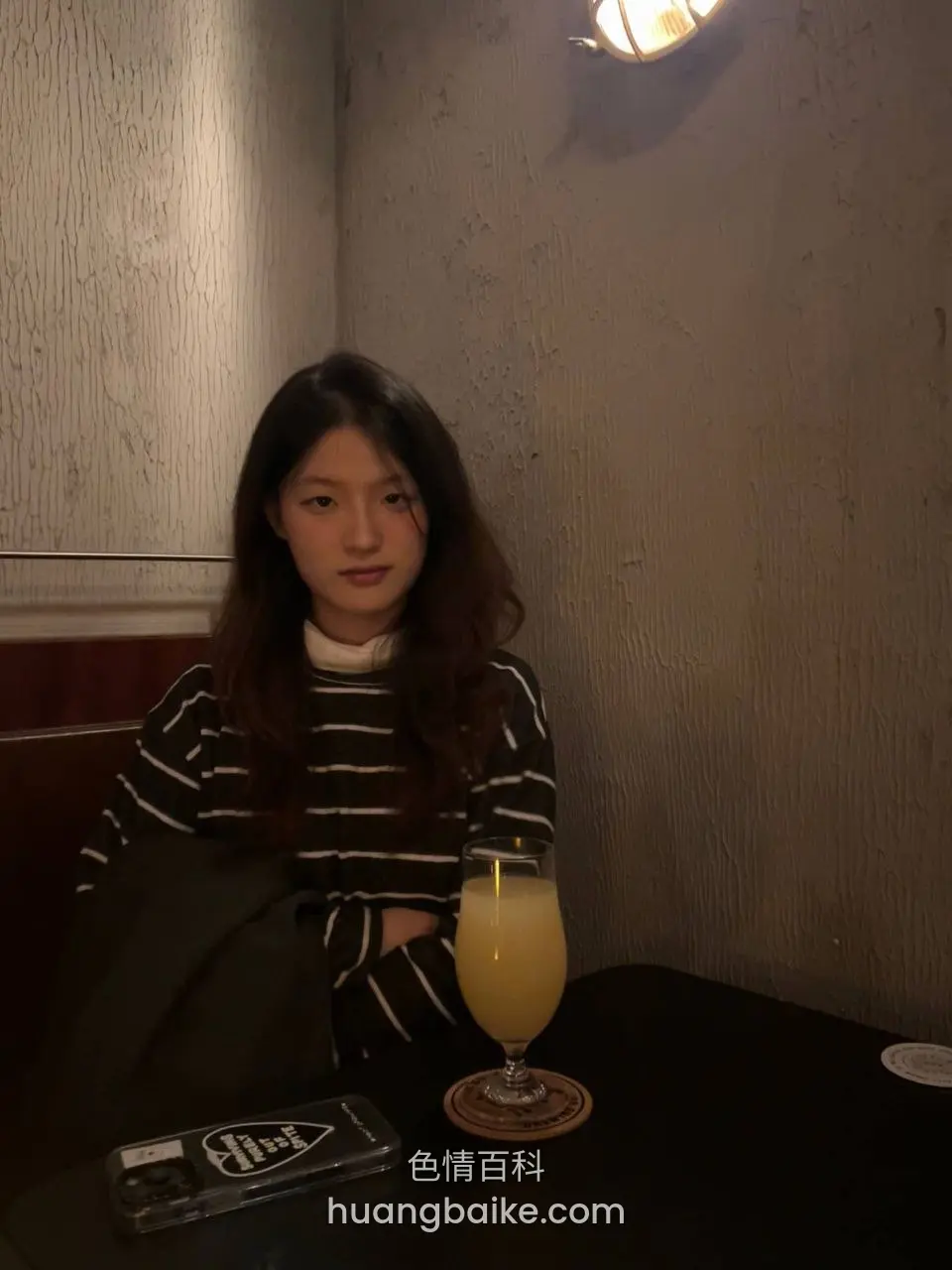 桌上橙汁玻璃杯，旁边放手机壳和外套
