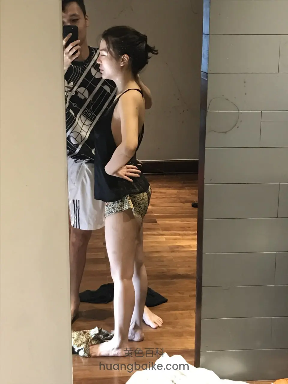举手机自拍镜子前，她侧身站着双手扶腰