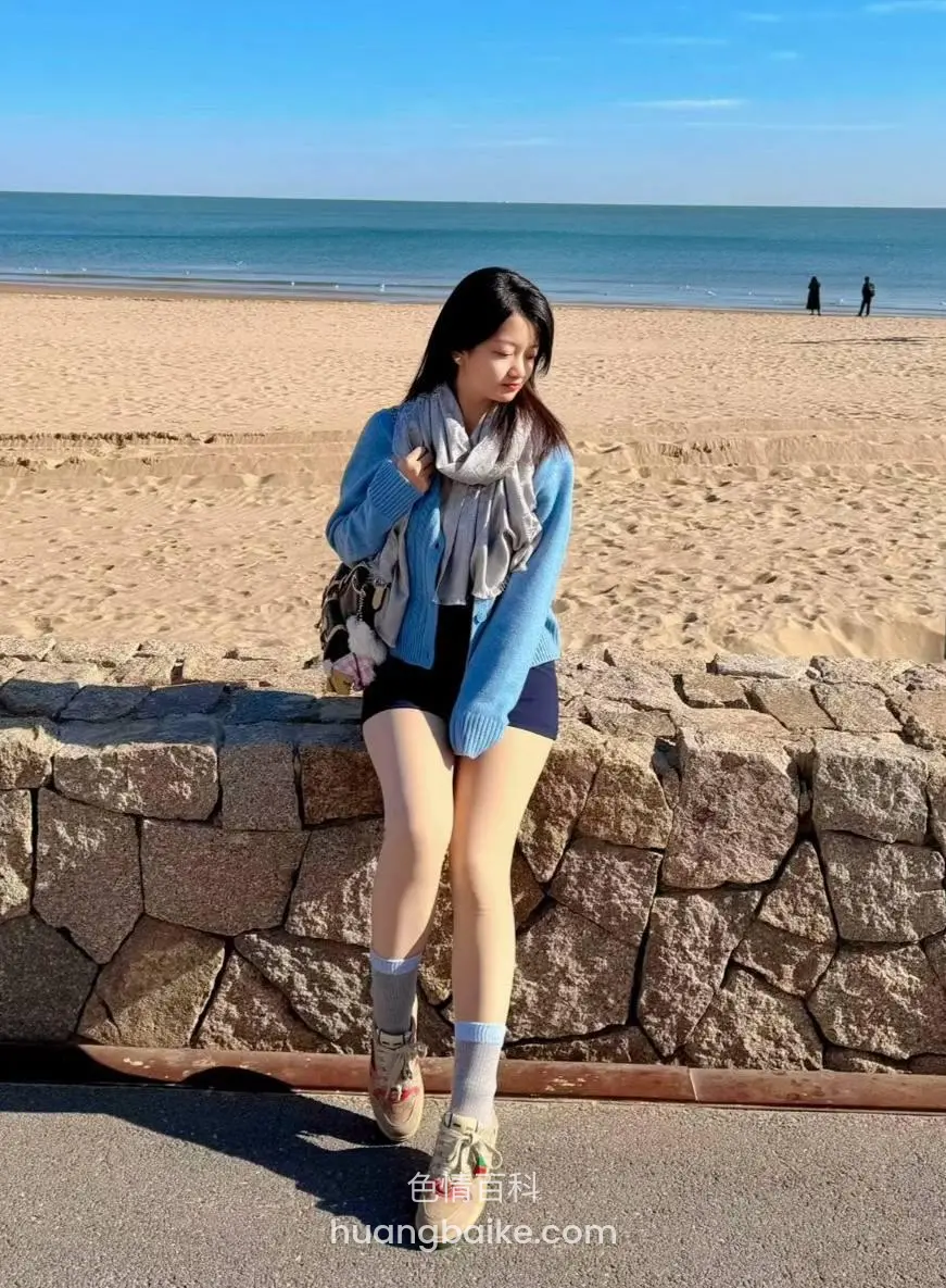 海滩石墙上坐着，望着脚边